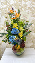 Frutero con flores y orquídeas en pecera de vidrio con frutas frescas en Bucaramanga